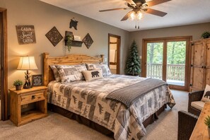 Ein Schlafzimmer mit einem Bett, einem Nachttisch, einer Lampe, einem Deckenventilator und Blick ins Freie.