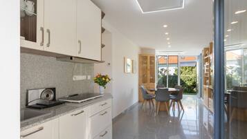 A modern kitchen with granite countertops, white cabinetry, and a dining area with a glass door leading to a garden.
