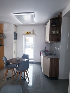 Eine kleine Küche mit Essbereich, einem eingebauten Backofen und einem Fenster, das für natürliches Licht sorgt.