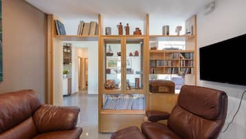 A living room with leather armchairs, a wooden bookshelf, and a flat-screen TV.