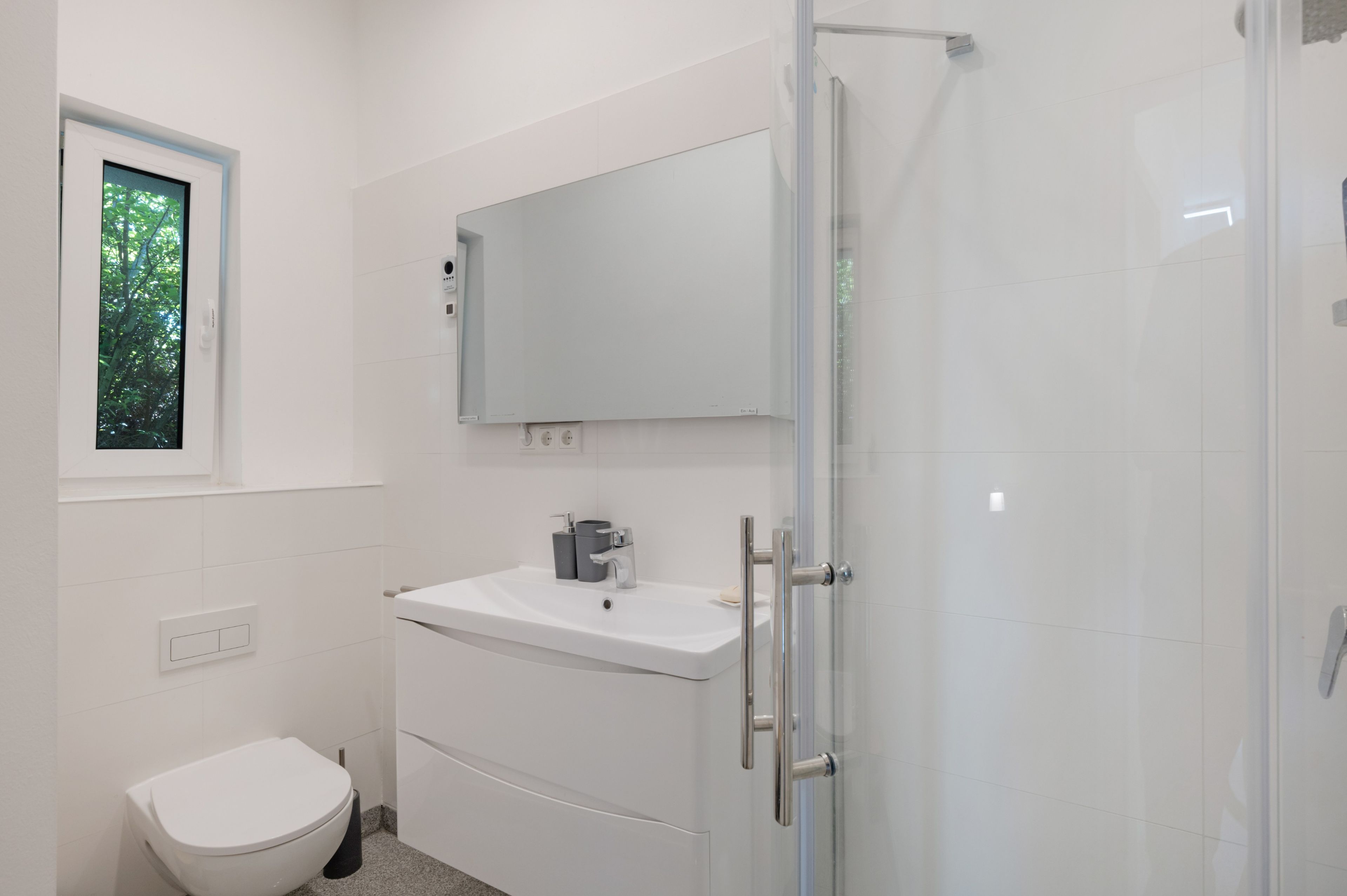 Ein modernes Badezimmer mit Toilette, Waschbecken und Dusche.