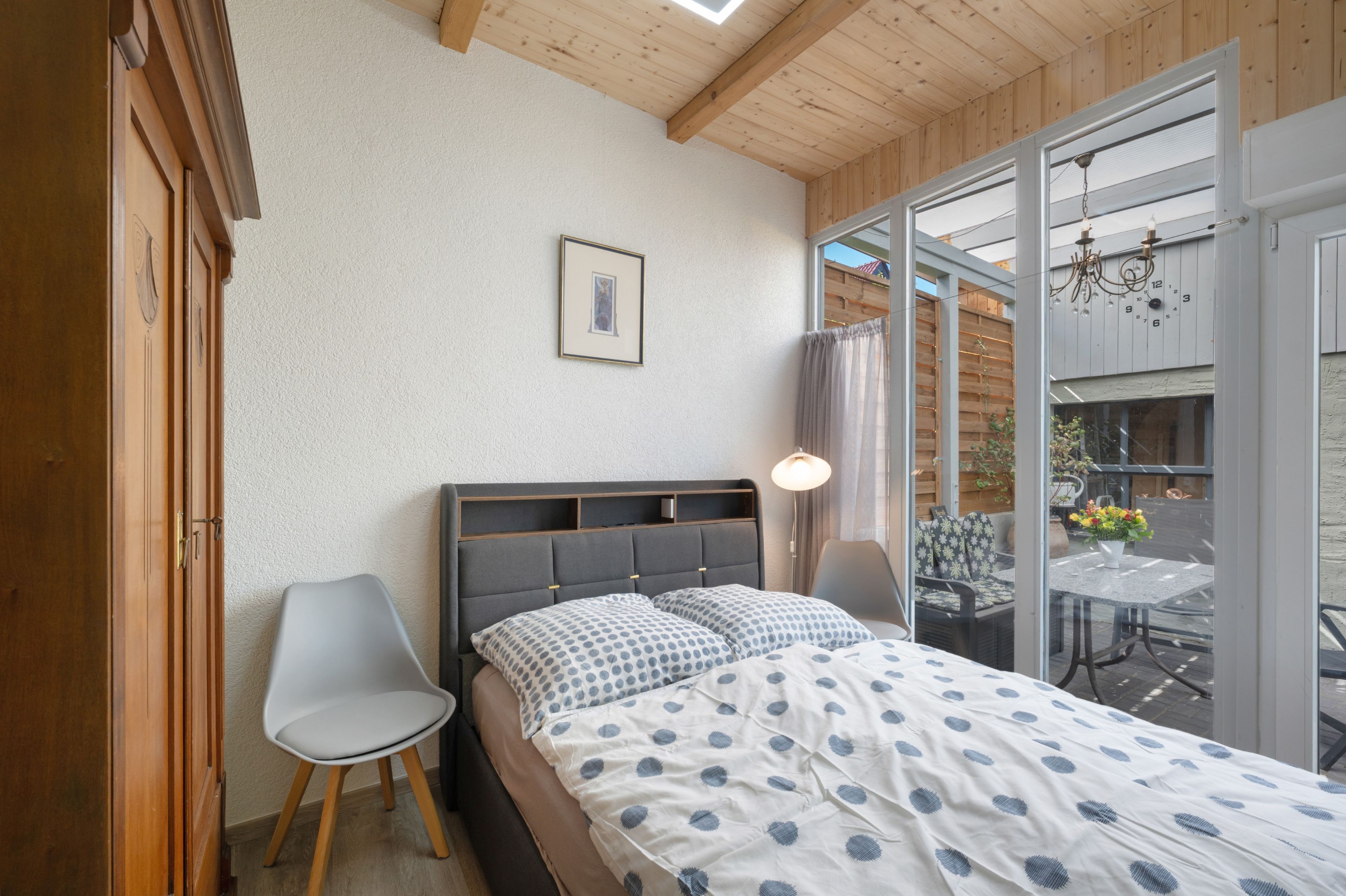 A bedroom with a bed, a chair, a window, and a picture on the wall.