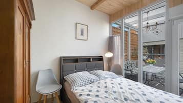 A bedroom with a bed, a chair, a window, and a picture on the wall.