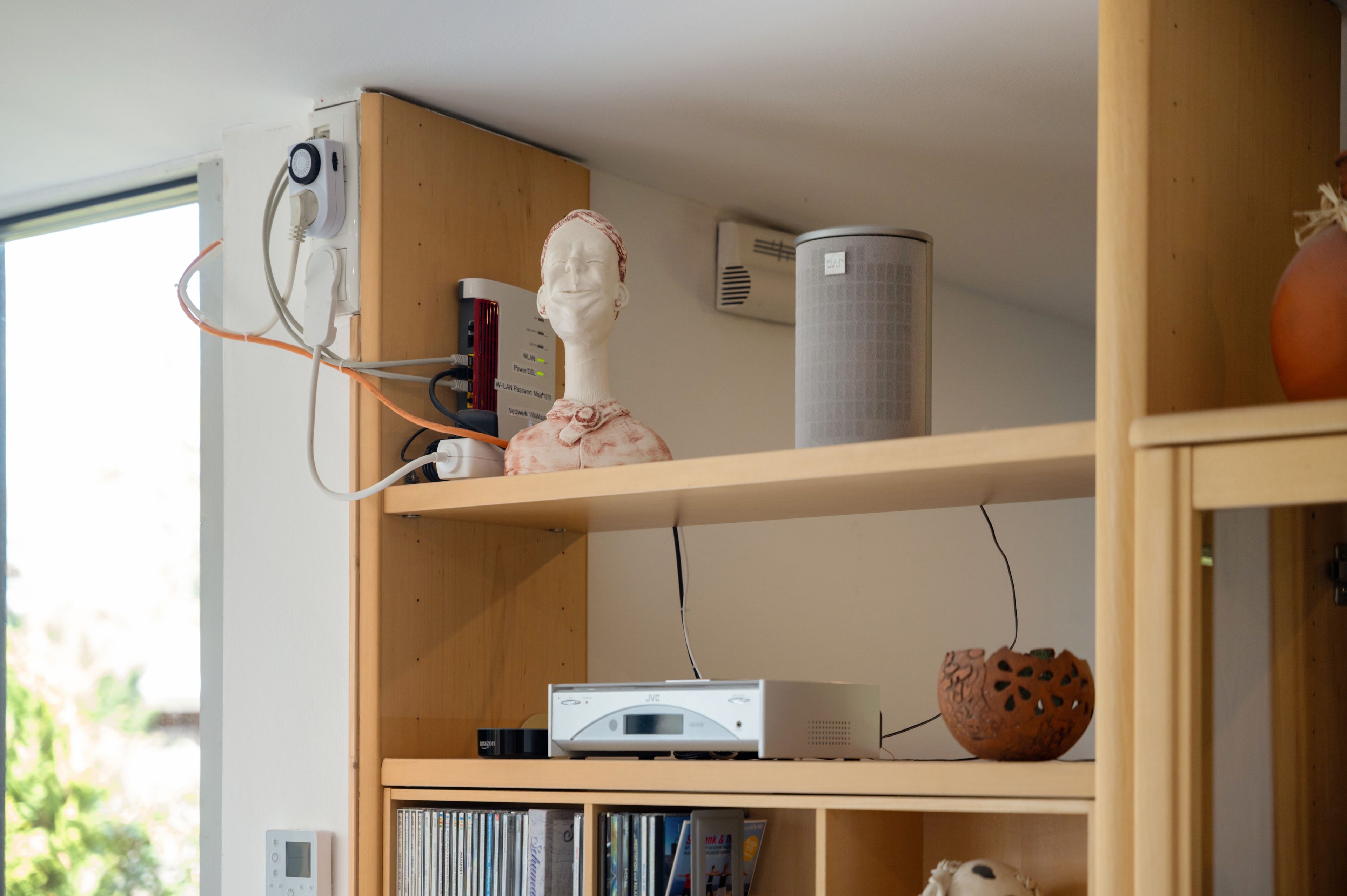 Een kamer met een houten plank waarop een wit voorwerp, een wit apparaat en een grijze, cilindervormige object liggen.