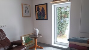 Uma sala de estar com um sofá de couro marrom, uma mesinha redonda com um vaso e duas obras de arte emolduradas na parede.