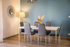 Un comedor con una mesa, sillas, una lámpara y un espejo decorativo.