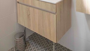Un baño moderno con tocador blanco, espejo y lavamanos.
