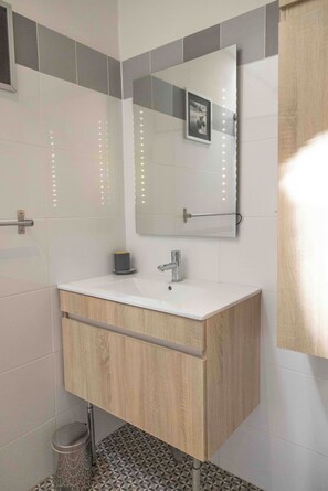 Un baño moderno con tocador blanco, espejo y lavamanos.