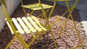 Un juego de mesa y silla de metal amarillo con una pequeña planta en maceta encima.