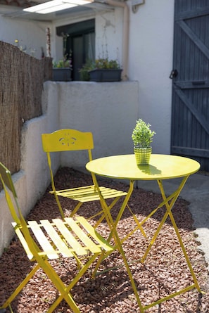 Un juego de mesa y silla de metal amarillo con una pequeña planta en maceta encima.