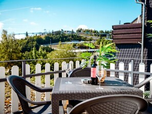 An outdoor dining area with a table, chairs, and a view of a bridge and greenery. - Holiday Apartment 708 (Winterberg)