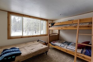 Eine kleine, einfache Unterkunft mit Etagenbett, Einzelbett, einem Fenster mit Jalousien und Teppichboden.