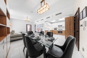 A modern dining area with a glass table, black chairs, and a chandelier. - StayShort - Peaceful 2-bedroom in Al Furjan that Sleeps 6! (Al Furjan)