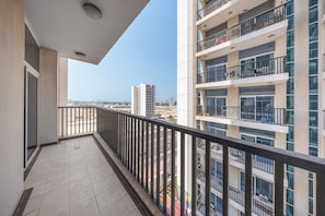 A balcony with a tiled floor and a railing, overlooking a cityscape with high-rise buildings. - StayShort - Peaceful 2-bedroom in Al Furjan that Sleeps 6! (Al Furjan)