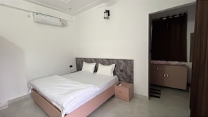 A bedroom with a bed, bedside table, and a wardrobe. - Farmgrill Restaurant And Party Lawn (Haldwani)