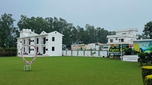 A grassy area with a heart-shaped decoration, a white building with multiple windows, and a sign for a restaurant. - Farmgrill Restaurant And Party Lawn (Haldwani)