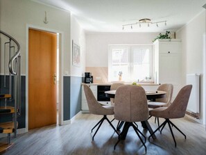 Una cocina moderna con comedor, que incluye una mesa redonda y cuatro sillas, una escalera y vistas al exterior.