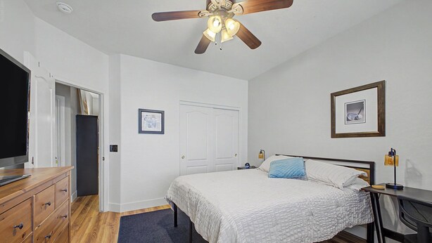 A bedroom with a bed, a desk, a chair, a television, a wardrobe, a ceiling fan, and a door. - Spacious 6-BR Furnished 30 day rental! Great Pool! (Chandler)