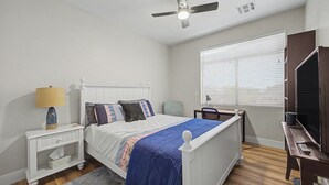 A bedroom with a bed, bedside table, lamp, chair, and a television. - Spacious 6-BR Furnished 30 day rental! Great Pool! (Chandler)