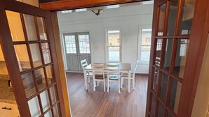 A room with a dining table and chairs, wooden flooring, and a view of the outside through a door. - The Walnut Inn, 2BR Handicap-Accessible Apt. Located in Parsons; Pet Friendly (Parsons)