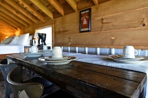 Un tavolo in legno apparecchiato con piatti e tazze, una panca e un cartello incorniciato appeso al muro.
