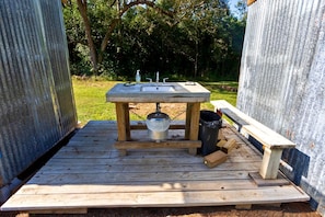 Una cucina esterna portatile completa di lavello, rubinetto e cestino.