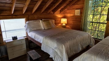 Une chambre à coucher dans un chalet en bois, avec un lit, une table de chevet et une fenêtre donnant sur la forêt.