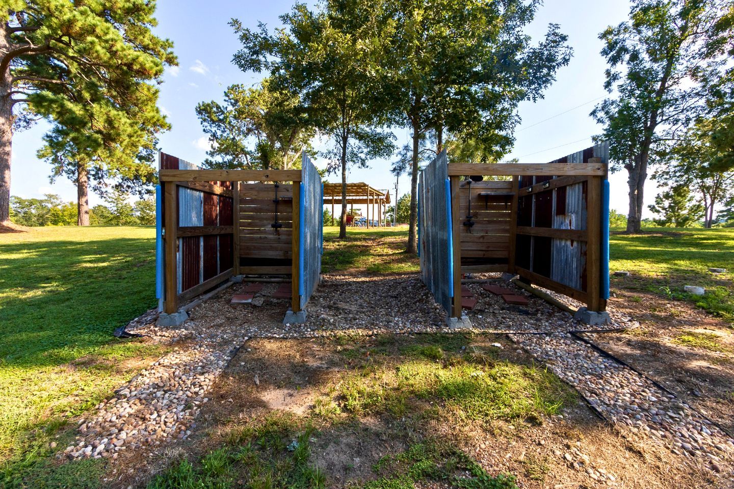 A wooden structure with a covered entrance, surrounded by trees and gravel.