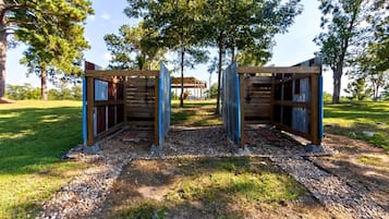 A wooden structure with a covered entrance, surrounded by trees and gravel.
