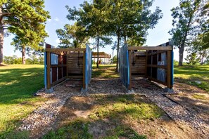 A wooden structure with a covered entrance, surrounded by trees and gravel.