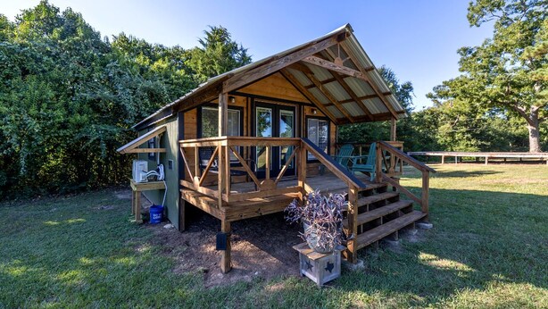 Een houten hut met een veranda, een klein terras en een omheinde tuin.