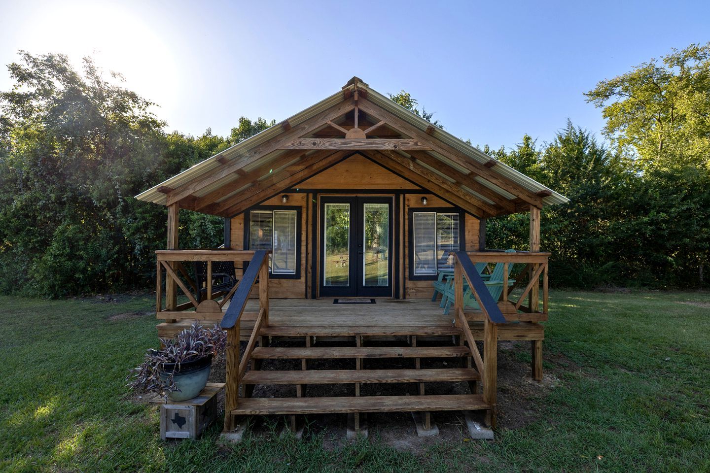 A wooden cabin with a porch, steps, and a door.