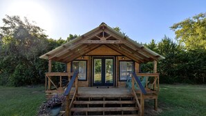 Een houten chalet met een veranda, een trap en een deur.