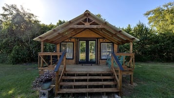 A wooden cabin with a porch, steps, and a door.