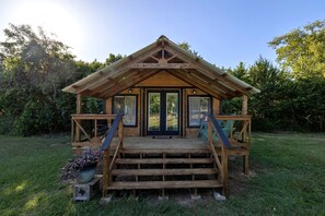Una baita di legno con portico, gradini e una porta.