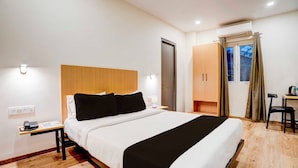 Ein Hotelzimmer mit Bett, Nachttisch, Lampe und Schreibtisch mit Stuhl.