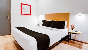 Ein Hotelzimmer mit einem Bett, einem Nachttisch und einem gerahmten Bild an der Wand.