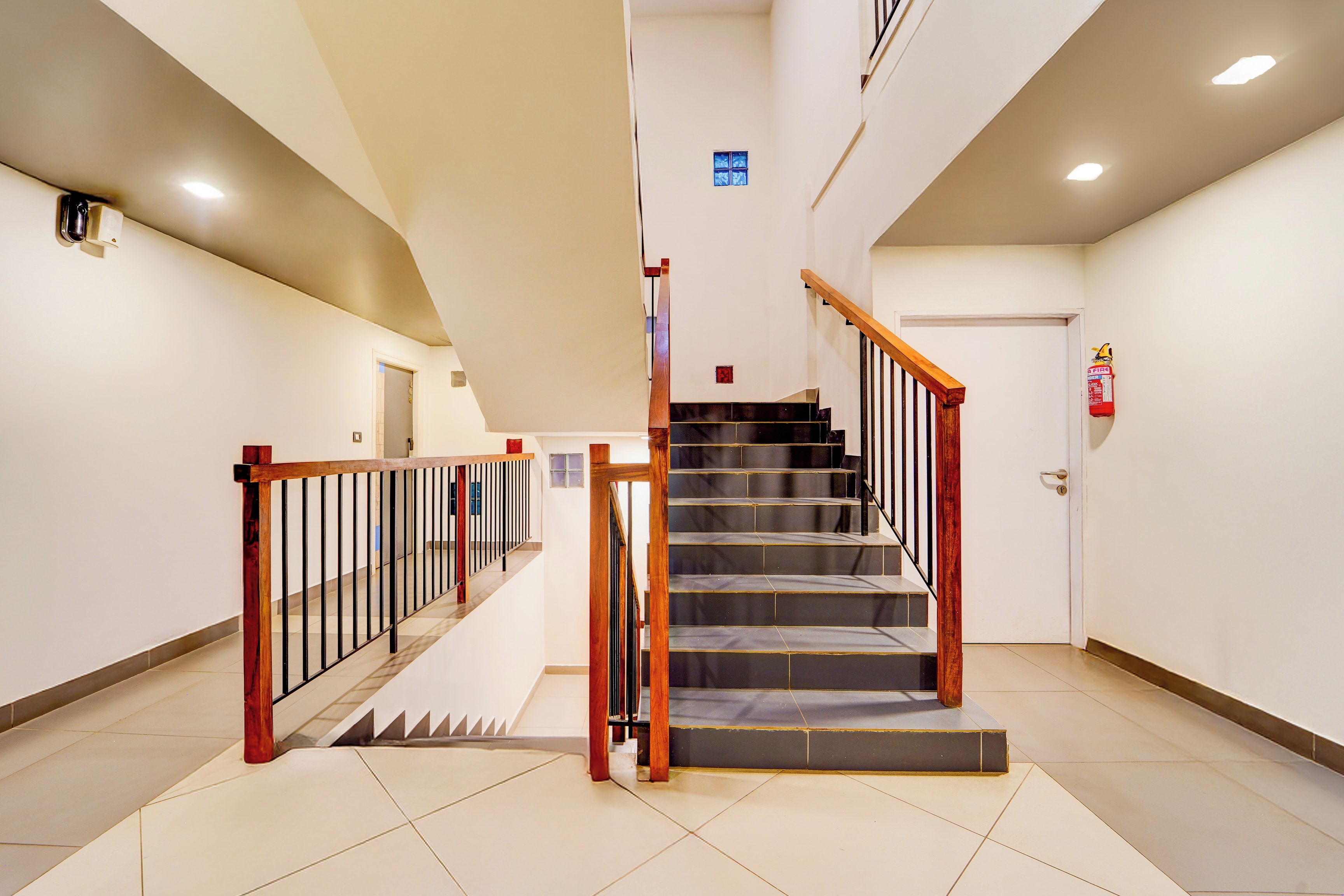 Una escalera con barandillas de madera y un extintor en la pared.