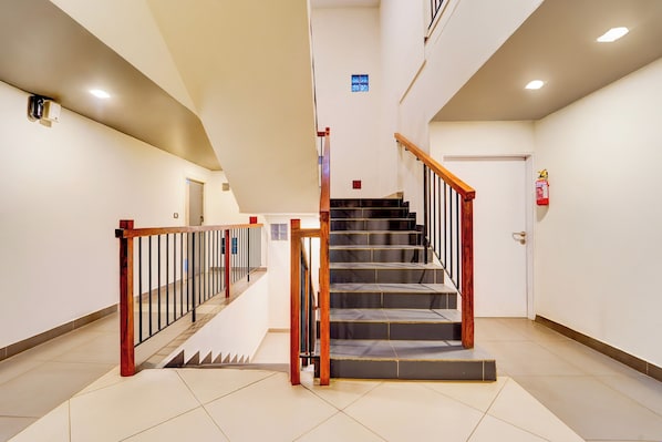 A staircase with wooden handrails and a fire extinguisher on the wall.