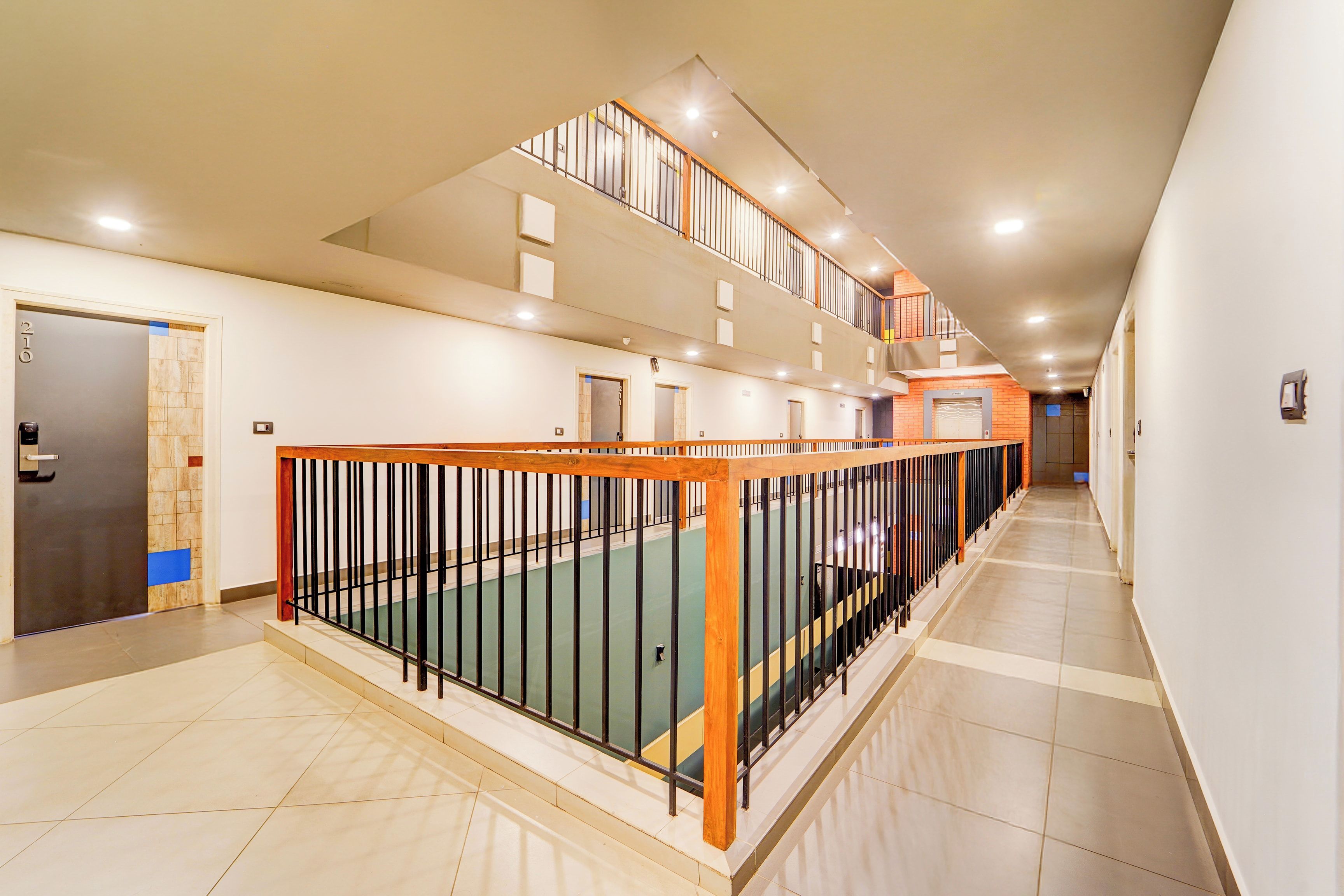 A multi-level interior with a staircase, a door with a number, and a wall-mounted light fixture.