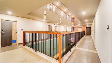 A multi-level interior with a staircase, a door with a number, and a wall-mounted light fixture.