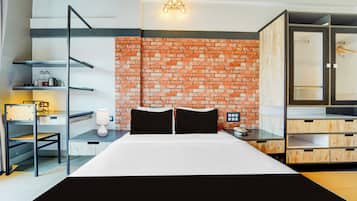 Een moderne hotelkamer met een bakstenen muur, een bed met zwart-wit beddengoed, een bureau met een lamp en een kledingkast.