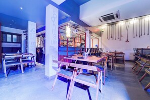 Interior de restaurante con mobiliario de madera, una zona de bar y cadenas colgantes.
