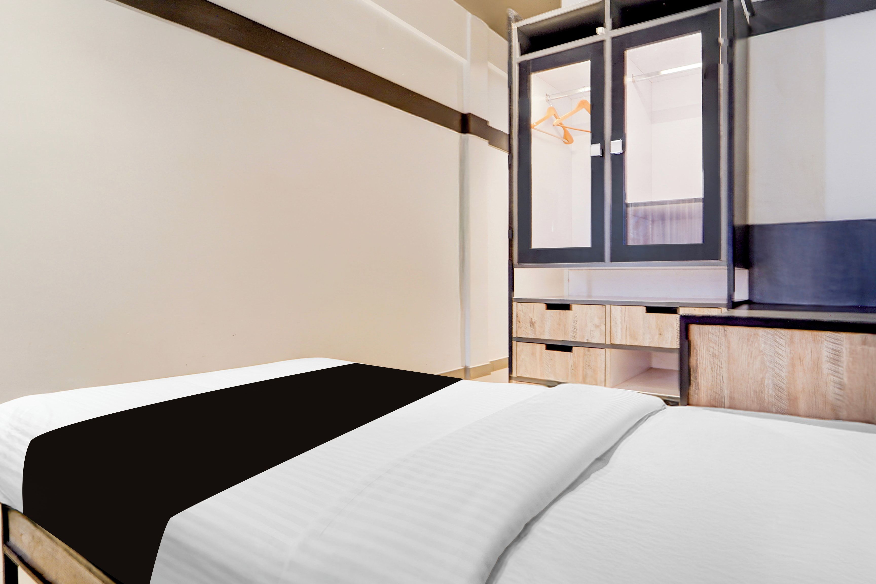 Una habitación de hotel con una cama, un armario y un espejo.