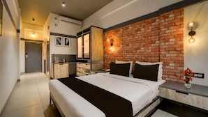Habitación de hotel moderna con pared decorada en ladrillo, una cama grande con ropa de cama blanco y negro, una mesita de noche con un jarrón de flores y un armario empotrado con espejo.