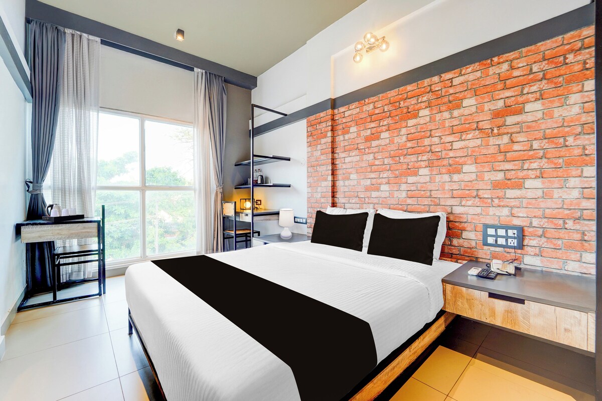 Una habitación de hotel moderna con una cama grande, un escritorio y una pared de ladrillo.