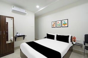 Una habitación de hotel con cama, mesita de noche, espejo, armario y aire acondicionado.