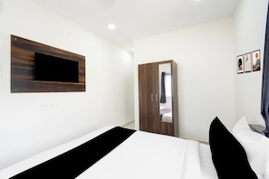 A bedroom with a bed, a wardrobe, a mirror, and a wall-mounted TV. - Townhouse Oak Meetpet Priyadarshani Park (Hyderabad)