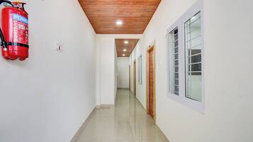 A hallway with a fire extinguisher mounted on the wall, wooden ceiling, and doors leading to rooms.