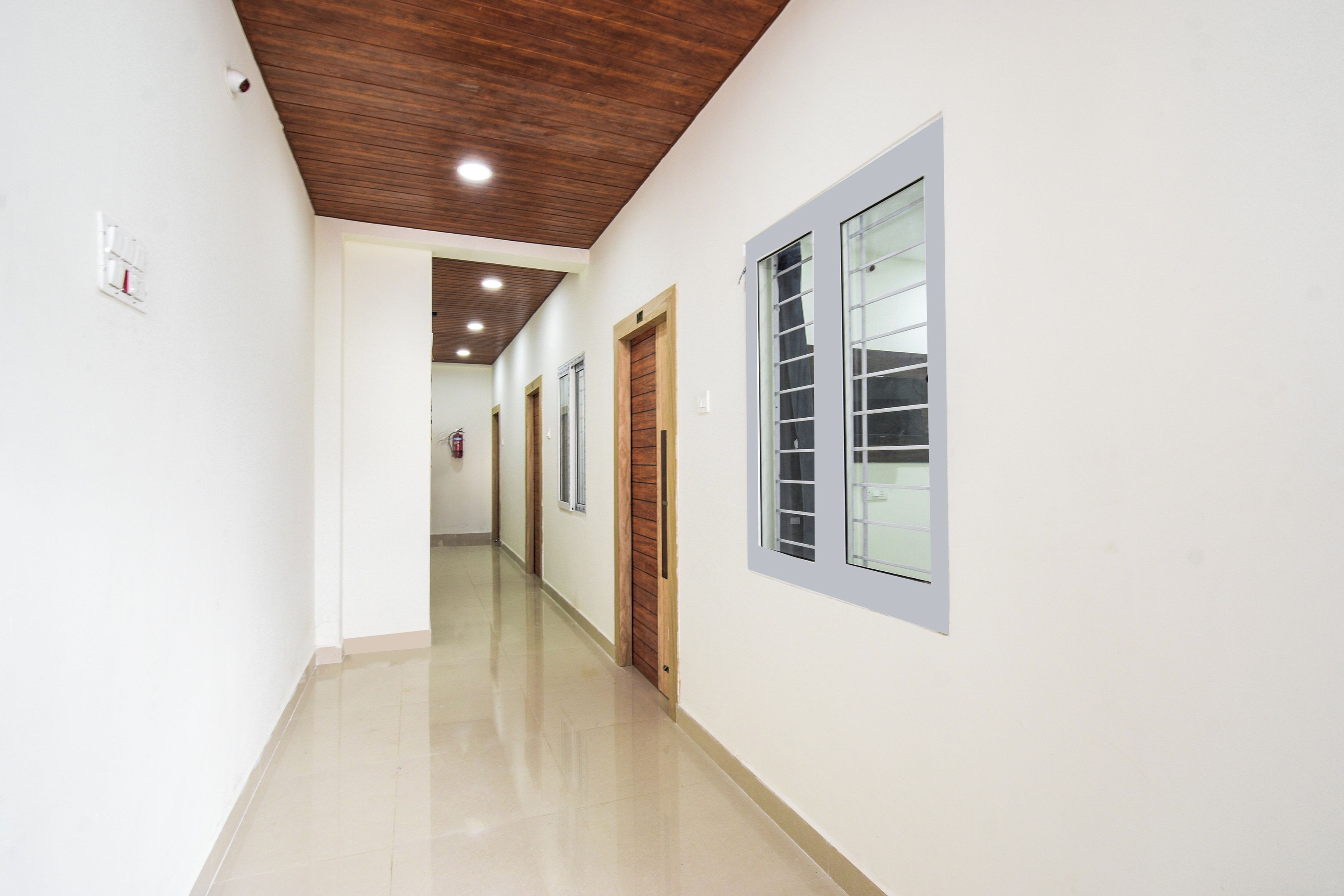 A corridor with wooden ceiling, white walls, and a tiled floor.
